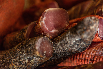 Variety of processed cold meat products with condiments. Assortment of different cold meats in a basket
