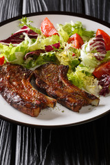 Honey lamb chops served with fresh vegetable salad close-up on a plate. vertical