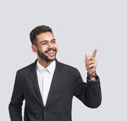 Portrait of handsome smiling young businessman pointing up. Laughing joyful cheerful men isolated studio shot