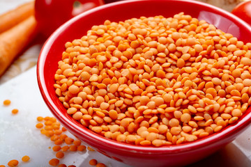 Dried orange lentils legume in red bowl