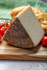 Italian cheese, piece of mature Tuscan Pecorino sheep cheese served with olive bread and tomatoes