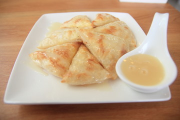 Roti and Milk in white dish on the wooden table.