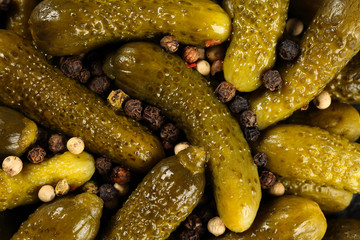 Top view, extreme close up of pickled gherkins (small cucumbers) sprinled with peppercorn mix. Macro food texture background