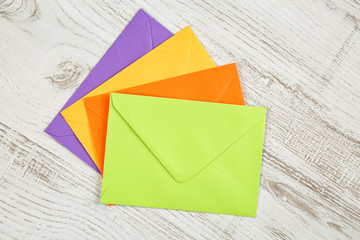 Top view of four colorful sealed envelopes from recycled paper on a white rustic wooden table