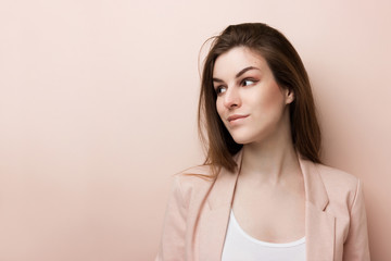 Young pretty business woman standing and looks away isolated on pink background