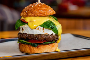 Close up tall tasty burger with cheese served on tray