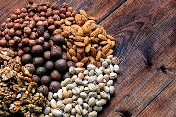 varied assorted nuts on wooden background top view, closeup