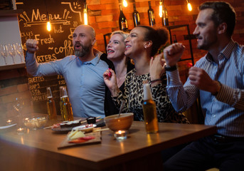 Group of friends watching tv in a cafe behind bar counter