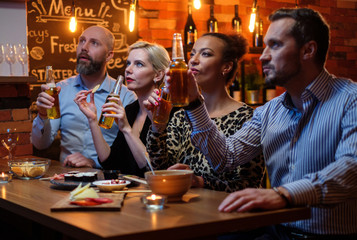 Group of friends watching tv in a cafe behind bar counter