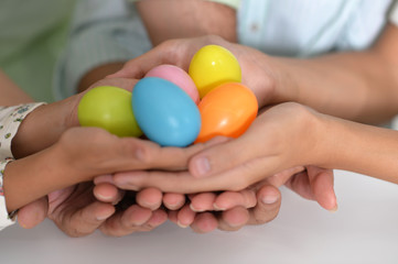 Naklejka premium Hands of 4 people holding colorful easter eggs close-up