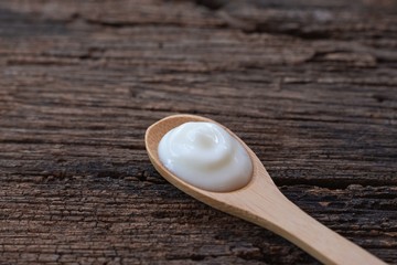 Natural homemade plain organic yogurt in wood spoon on wood texture background