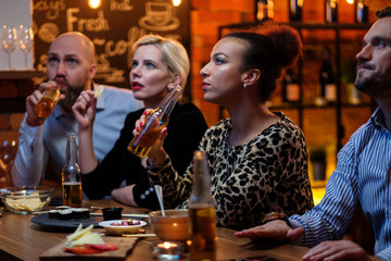 Group of friends watching tv in a cafe behind bar counter