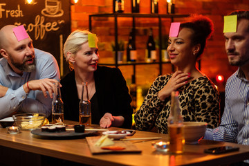 Group of friends playing sticky head game behind bar counter in a cafe