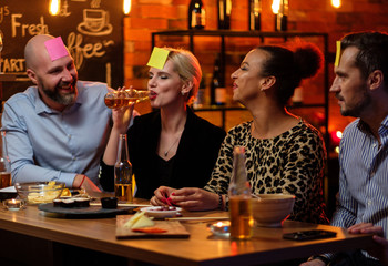 Group of friends playing sticky head game behind bar counter in a cafe