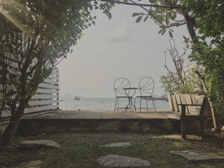 Two garden chairs and table set at the backyard with sea view.