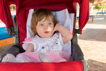 Baby girl in carriage on resort on the beach