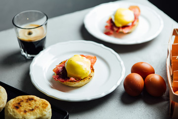 Two portions of the egg benedict served on a grey table