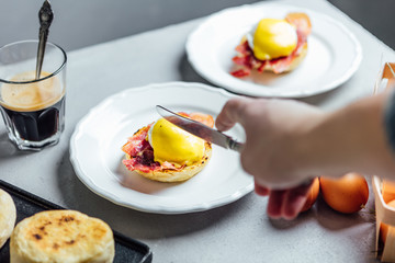 Man's hand is prepared to make a cut on the poached egg