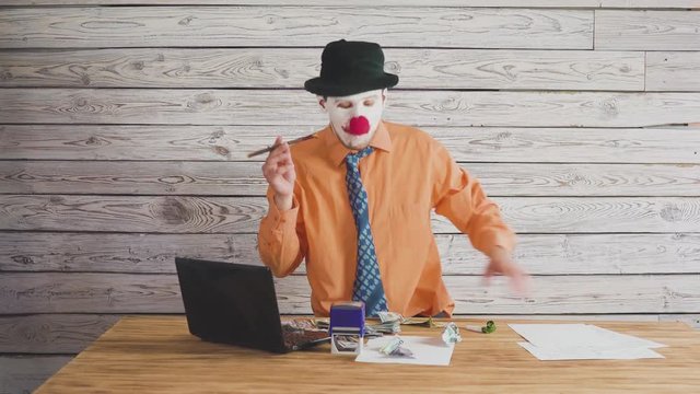Clown businessman near the director's table swears at subordinates. Concept on angry stupid boss