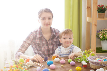 Happy family Mom and children son paint easter eggs with colors. Preparation for holiday.