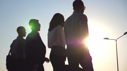 Group of young businessmen walking in city street at sunset time. Colleagues being on his way to home after hard day work. Sun flare at background. Success concept. Slow motion Close up Rear back view