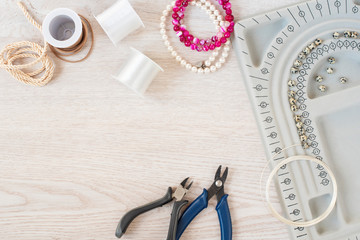 Jewelry designer workplace. Handmade, craft concept. Materials for making jewelry. Beading bracelets and necklaces settings. Freelance workspace in flat lay style