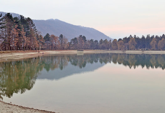 trees growing along the lake are reflected in the water, the landscape
