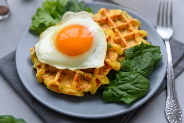 Spinach cheese waffles with fried egg on gray wooden background. Selective focus.