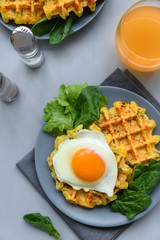 Spinach cheese waffles with fried egg on gray wooden background. Selective focus. Top view.
