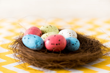 Nest with colorful painted easter eggs on yellow surface