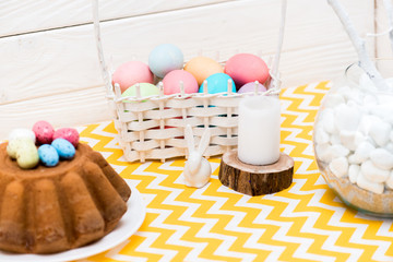 Easter cake, painted eggs, candle and ceramic bunny on table