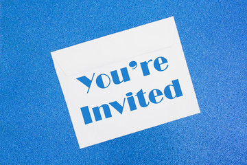 You're Invited message on white envelope on blue