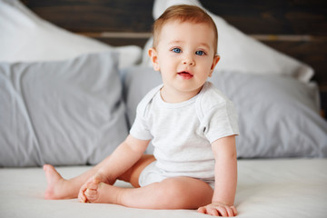 Portrait of cute baby sitting on bed - Powered by Adobe