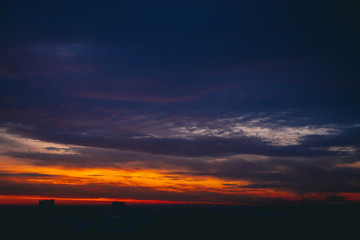 Cityscape with wonderful varicolored fiery dawn. Amazing dramatic multicolored cloudy sky. Dark...