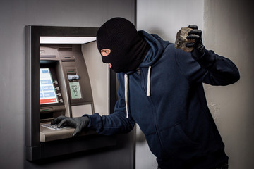 thief with a stone robs an ATM