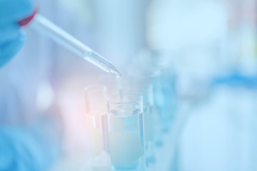 Women scientist doing some research with dropper chemical in tube.