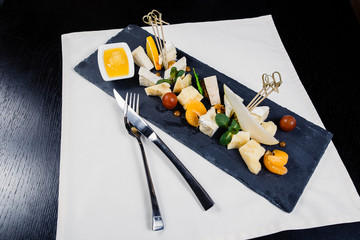 cheese plate assortment of various types of cheese on dark slate cutting board