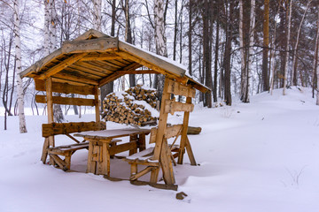 Wooden gazebo in the snow-covered forest