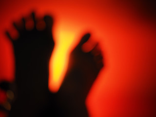 Blurry man’s two feet with yellow light has a red background. The middle of dark atmosphere,...