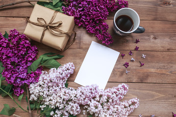 Obraz na płótnie Canvas Bouquet of lilac flowers on wooden table with blank card for text , gift, coffee. Flat lay