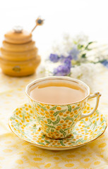 A cup of  hot green tea with a honey jar