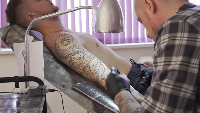 A man makes a tattoo in the salon.