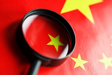 The flag of the CHINESE PEOPLE'S REPUBLIC is looking through a magnifying glass. The study of the...