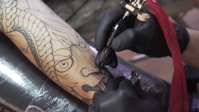 Tattooist makes a tattoo. Closeup, tattoo salon.