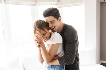 Portrait of excited couple laughing and hugging together while having fun at home