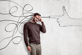 Thinking young man in casual clothes with a hand shooting gesture and abstract lines drawn on white wall background