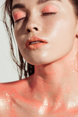 beautiful stylish girl with coral glitter makeup and eyes closed isolated on grey