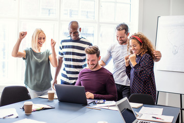 Excited coworkers cheering together during an office meeting - Powered by Adobe