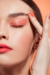 Naklejka premium beautiful stylish young woman with glitter makeup isolated on coral