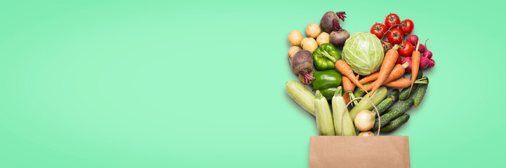 Paper shopping bag and fresh organic vegetables on a light green background. Concept of buying farm...